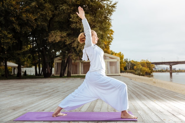 Foto la pose del guerrero. mujer joven y segura de pie en la pose de yoga guerrero