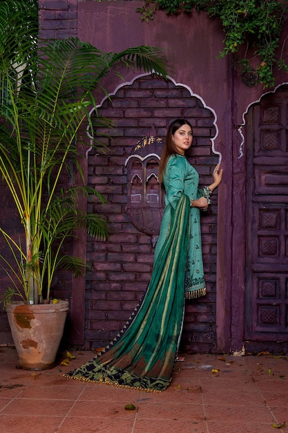 Pose lateral de atitude de menina asiática gostosa usando vestido tradicional verde para sessão de fotos de moda