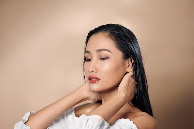 Pose de modelo de cara de tacto de mano de mujer asiática elegante hermosa atractiva en sesión de fotos de estudio aislado fondo blanco