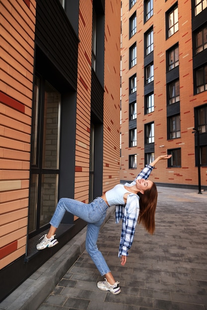 Pose de mujer de moda en la ciudad entre los edificios de la moda.