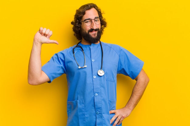 Pose orgulhosa do homem novo da enfermeira contra o fundo amarelo