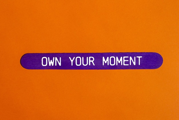 Poseer su propio mensaje de momento escrito en un palo de madera púrpura con fondo naranja Conceptual poseer su propio símbolo de momento Copiar espacio