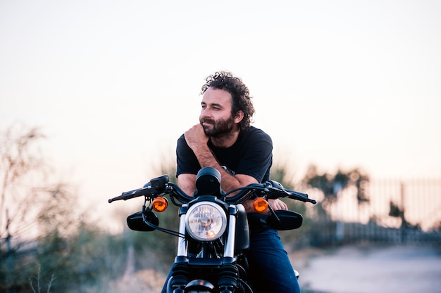 Poses de homem em sua motocicleta ao pôr do sol