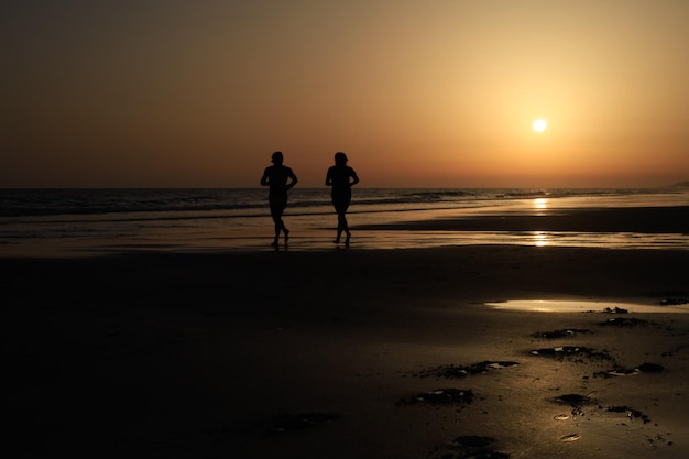 posibilidad remota de dos corredores en una playa española con una puesta de sol increíble