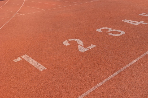 Posición corredor atleta punto de inicio fila de número en pista de atletismo estadio deportivo posición comercial concepto de inicio