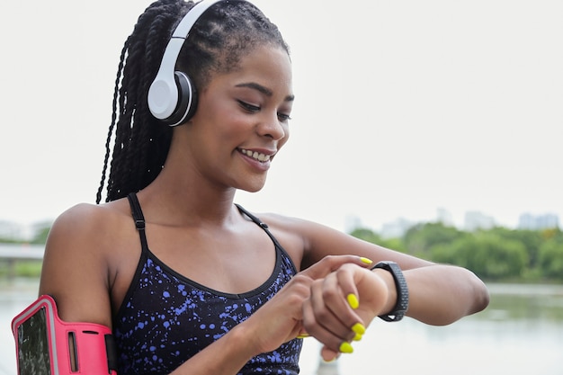 Posicionando a la joven deportista negra apuntando al rastreador de fitness en su muñeca