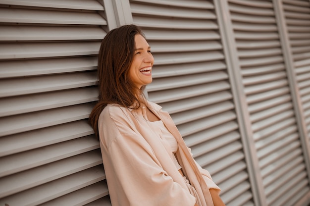 Posieren. Ein Bild einer jungen hübschen Frau in Beige in der Nähe der Wand