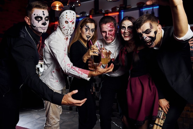 Posieren für die Kamera. Friends ist auf der thematischen Halloween-Party in gruseligem Make-up und Kostümen.