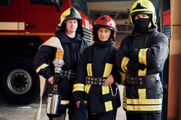 Posieren für eine kamera gruppe von feuerwehrleuten in schutzuniform, die auf station ist