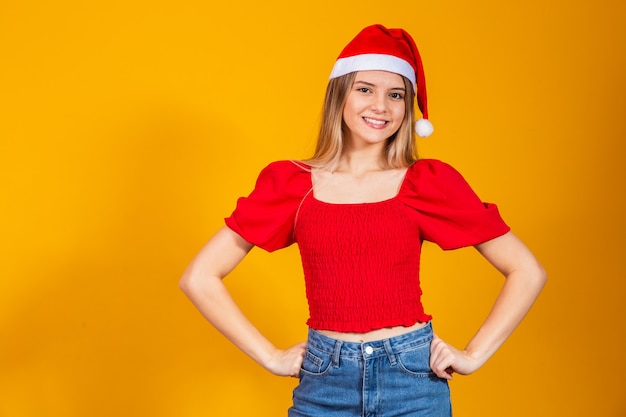 Positiva hermosa mujer rubia con gorro de Papá Noel y traje rojo para Navidad. Mujer joven vestida para Navidad sonriendo.