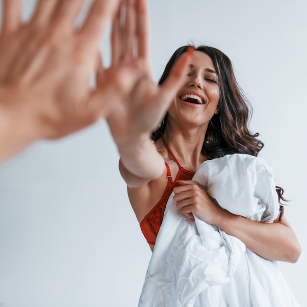 Positiva linda jovem morena de cueca no quarto branco dá mais cinco para a outra pessoa.