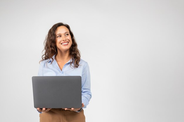 Foto positiva mujer de negocios caucásica del milenio escribiendo en la computadora hablando mirando el espacio vacío