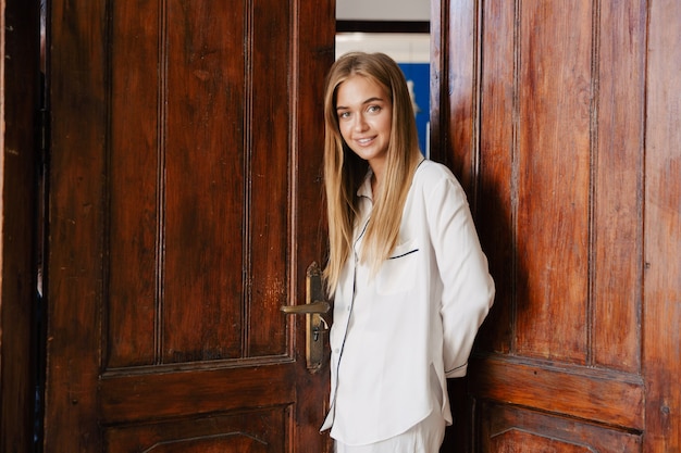 positiva otimista jovem linda garota de pijama em casa perto de portas de madeira.