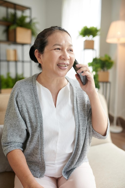 Positive ältere Frau, die am Telefon anruft