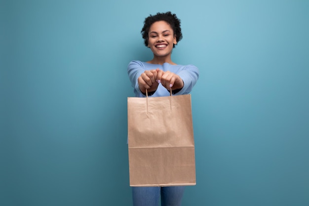 Positive brünette Frau mit Afro-Haaren hält eine recycelbare Basteltasche in der Hand