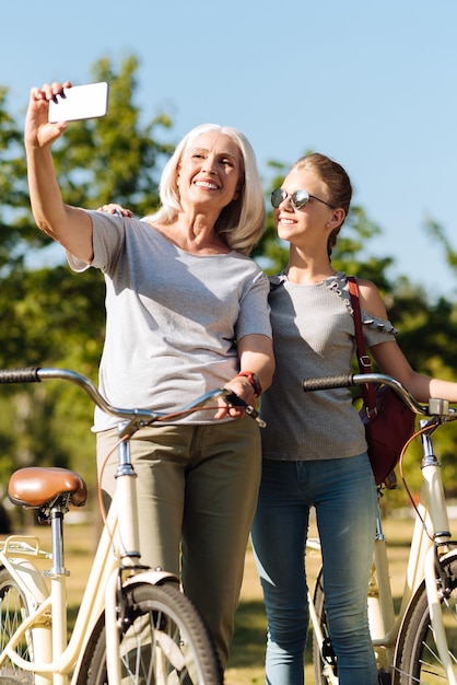 Positive Enkelin und ihre Großmutter im Park Fahrrad fahren