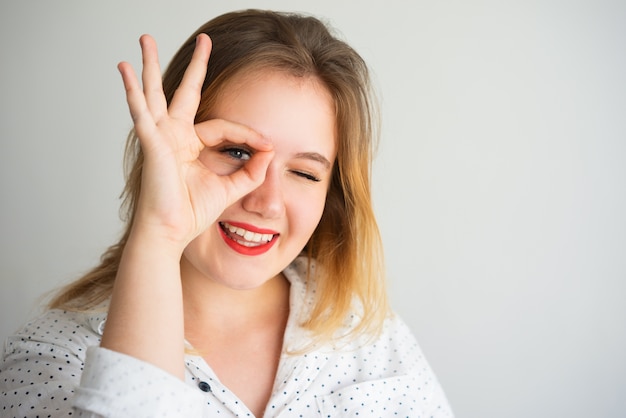 Positive erfolgreiche Frau, die durch Finger schaut