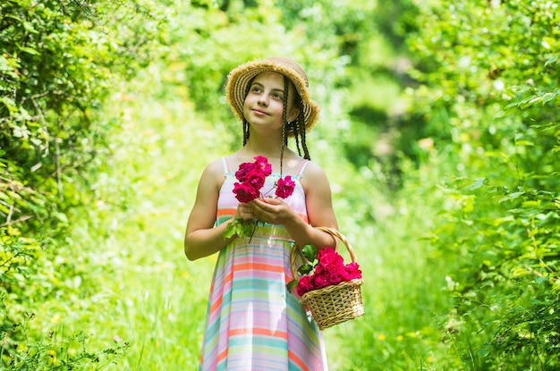 Positive Floristin Kindheit Glück glückliches Kind sammeln Blumen Kinderspaziergang im Frühling Park oder Garten kleines Mädchen mit Sommerrosenstrauß Sommerferien und Urlaub weibliche Schönheit und Mode