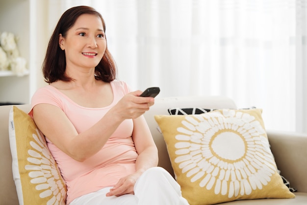 Positive Frau beim Einschalten des Fernsehers