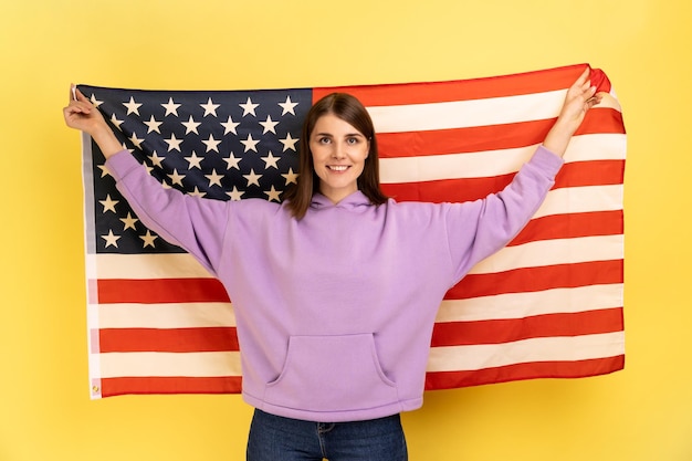 Positive Frau, die mit erhobenen Armen steht und die USA-Flagge hält, um den Nationalfeiertag zu feiern