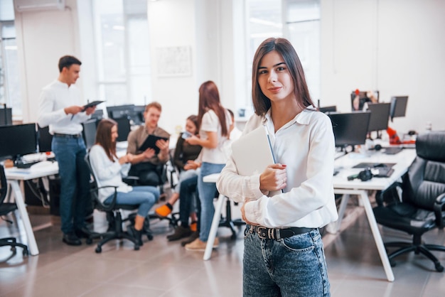 Positive Frau, die vor jungen Geschäftsleuten steht, die im modernen Büro zusammenarbeiten.