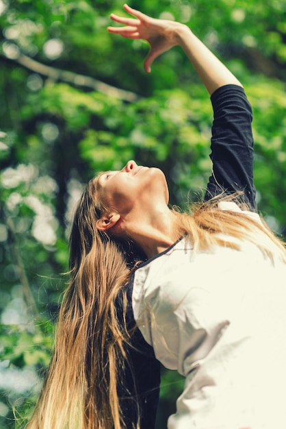 Positive junge Frau, die draußen Yoga macht