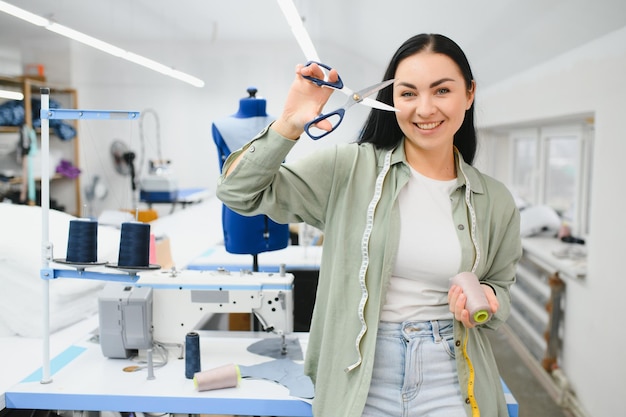 Positive junge Frau, die in der Werkstatt mit professioneller Maschine näht