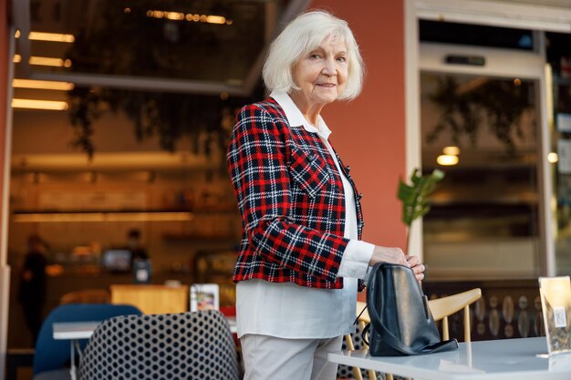 Positive lächelnde Frau im Ruhestand, während sie im Freien steht