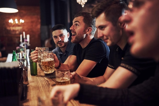 Positive Leute, Freunde, die sich mit Bier in der Hand im Pub ausruhen und sich unterhalten.