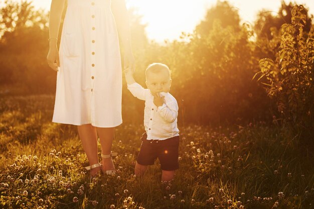 Positive Mutter mit ihrem Sohn verbringt an sonnigen Sommertagen Freizeit auf dem Feld