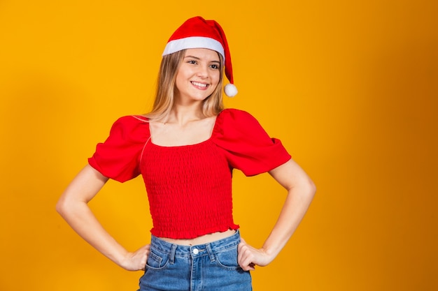 Positive schöne blonde Frau mit Weihnachtsmütze und rotem Outfit für Weihnachten. Junge Frau gekleidet für das Weihnachtslächeln.