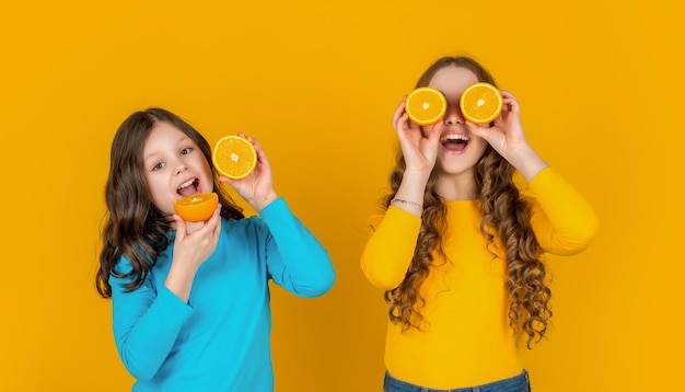 positive Teenager-Mädchen halten orangefarbene Früchte auf gelbem Hintergrund