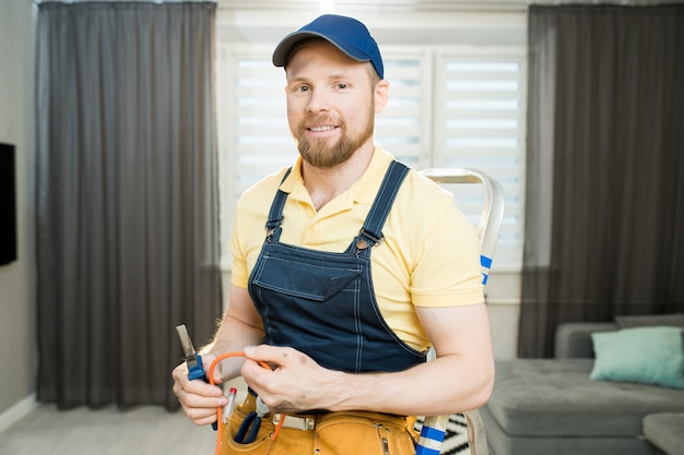 Positiver Elektriker repariert Drähte in der Wohnung