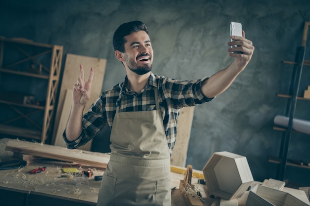 Positiver Erfolg Hartholzmöbel Restaurierung Unternehmer Arbeiter machen Selfie auf Smartphone Show V-Zeichen genießen seinen Arbeitsplatz in der Garage zu Hause