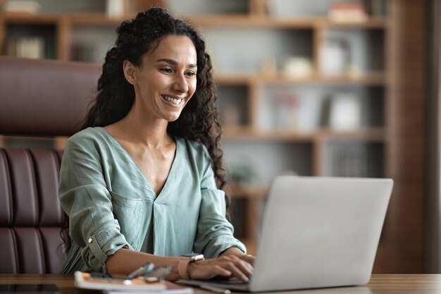 Positiver Freiberufler der jungen Frau, der zu Hause Laptop verwendet