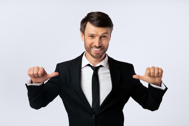 Positiver Geschäftsmann zeigt mit dem Daumen auf sich selbst im Studio