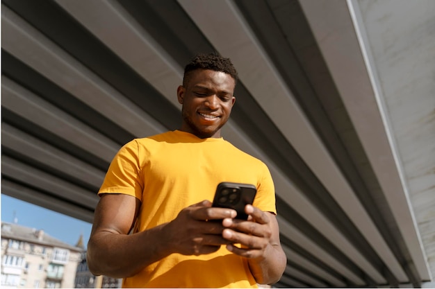 Positiver junger afrikanisch-amerikanischer Mann hält ein Handy und sieht sich ein Video auf einer Stadtstraße an