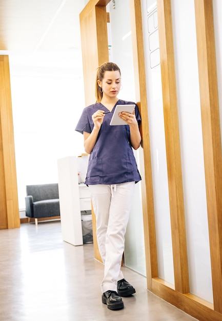 Positiver junger Arzt mit Tablet im Krankenhaus