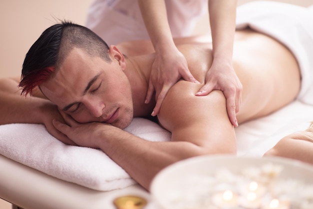 Positiver junger Mann mit einer Rückenmassage in einem Spa-Center