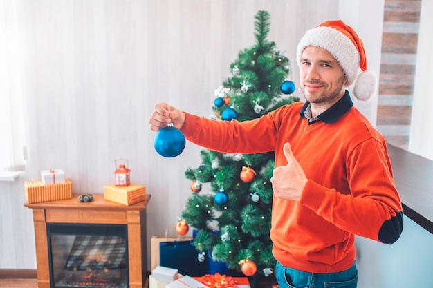 Positiver junger Mann steht und hält blaues Spielzeug in der Hand