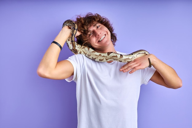 positiver Mann, der Schlange in Händen hält, keine Angst, keine Phobie. kaukasischer Mann im weißen T-Shirt, das mit Schlange aufwirft