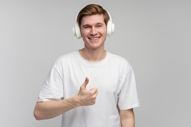 Positiver Mann mit Headset, der Musik hört und eine coole Geste zeigt