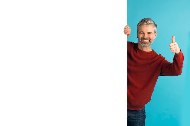 Foto positiver mann mittleren alters steht neben einem riesigen werbetafel-mockup