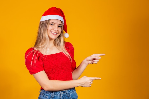 Positives Mädchen in Sankt-Hut, das auf Textraum zeigt. Förderung und Werbung auf gelbem Hintergrund isoliert.