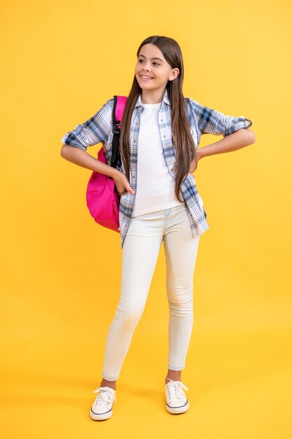 Positives Teenager-Schulmädchen auf Hintergrund. Foto eines Teenager-Schulmädchens mit Rucksack. Teenager-Schulmädchen isoliert auf Gelb. Teenager-Schulmädchen im Studio