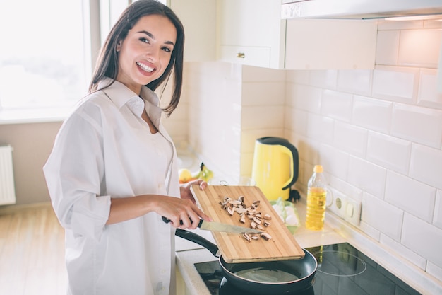 Positives und schönes Mädchen steht am Herd