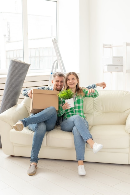 Positives verrücktes fröhliches Paar freut sich über den Umzug ihrer neuen Wohnung im Wohnzimmer mit ihren Sachen. Konzept der Einweihungsfeier und Hypotheken für eine junge Familie