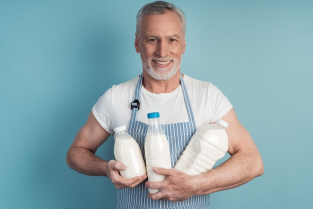 Positivo, sonriente, hombre mayor, tenencia, un, botella de leche, en, un, pared azul, aislado