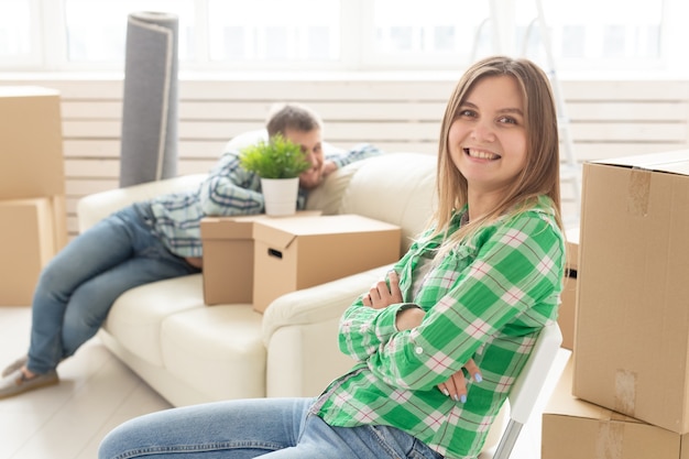 Positivo sonriente joven sentada contra su marido riendo borrosa en una nueva sala de estar mientras