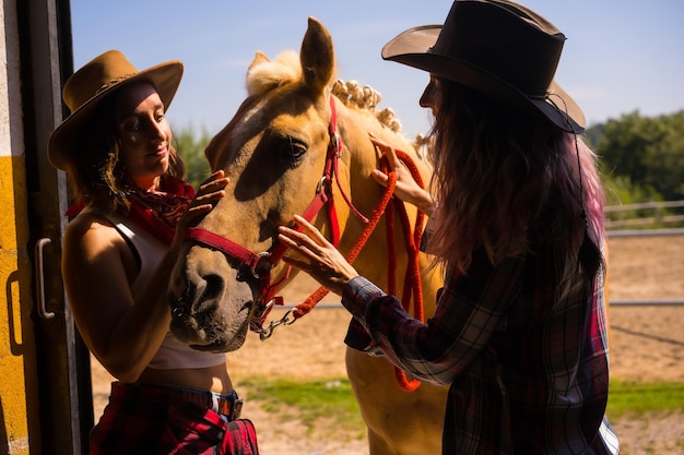 Posou na silhueta de duas mulheres vaqueiras entrando no estábulo com um cavalo de um cavalo com roupas sul-americanas